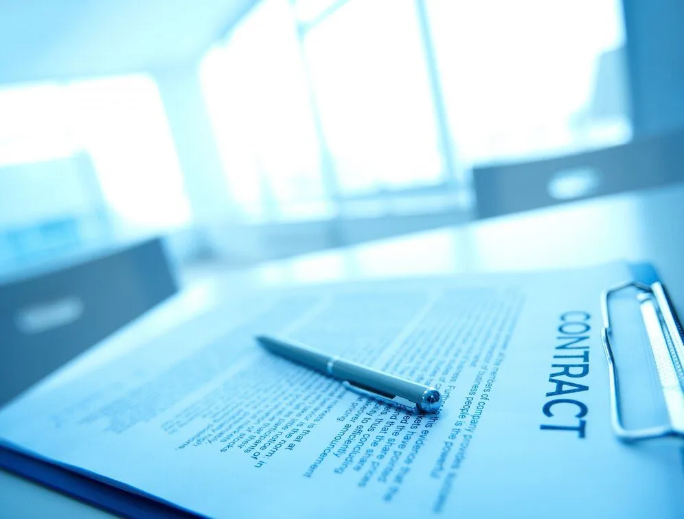A contract on a clipboard with a pen resting on top